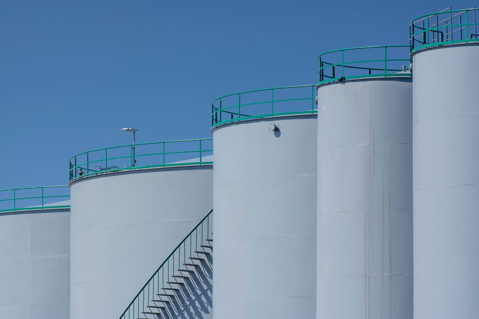 Industrial oil storage tanks under a clear sky